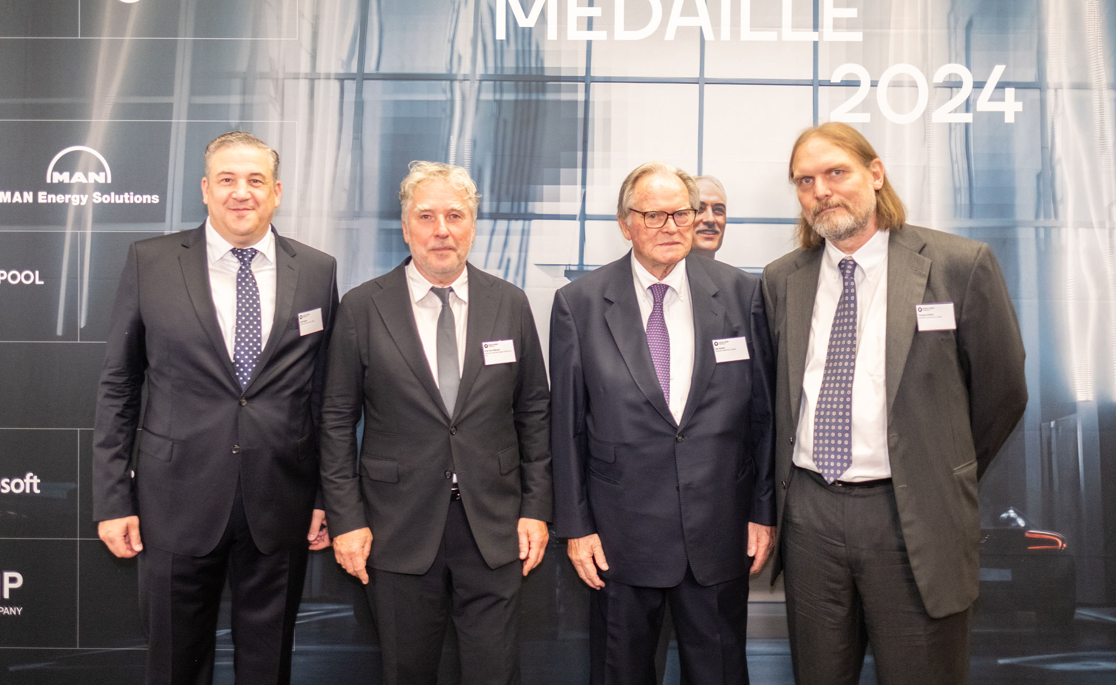 Veit Enders, Prof. Kurt Mehnert, Udo Schütz in front of the sponsor wall of the Diesel Medal 2024.